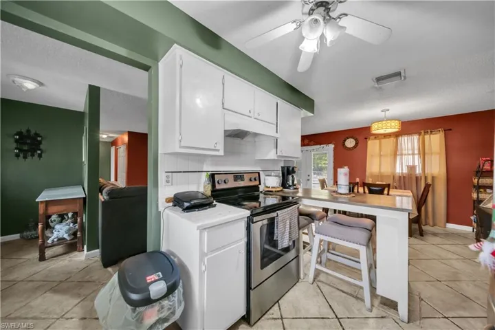 Kitchen featuring white cabinetry with brushed nickel hardware, a double basin stainless steel sink, a window with blinds, and white tile backsplash