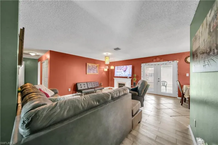 Spacious living area featuring wood-finish tile flooring, a contemporary ceiling light fixture, and a white baseboard trim