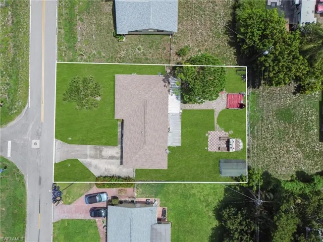 Expansive backyard featuring a green-painted storage shed with a gambrel roof, a checkered paver patio, a concrete counter area, and a large grassy area