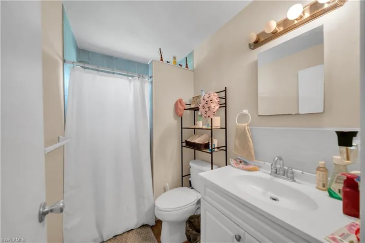 Bathroom vanity with a single basin sink, laminate countertop, and wood-finish cabinetry