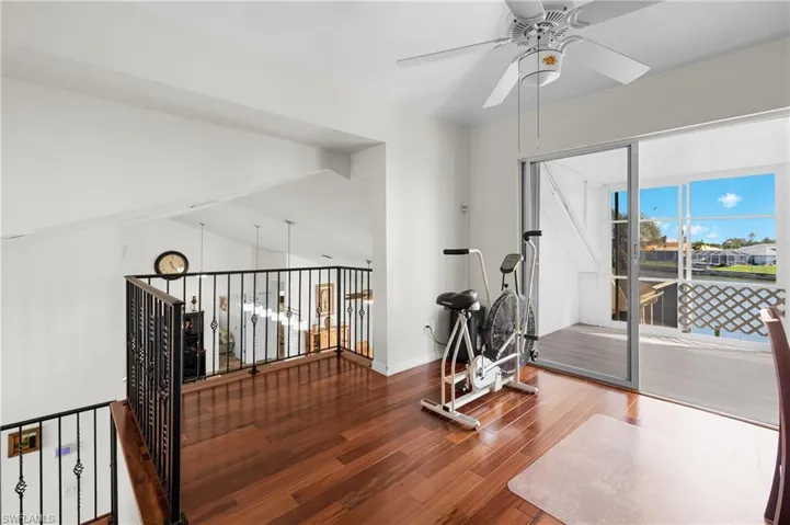 Exercise room featuring hardwood / wood-style floors, ceiling fan, and lofted ceiling
