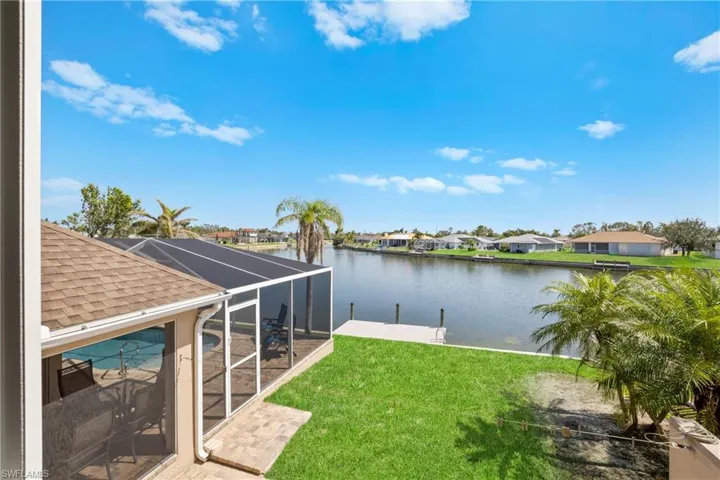 View of yard with a lanai, a water view, and a dock