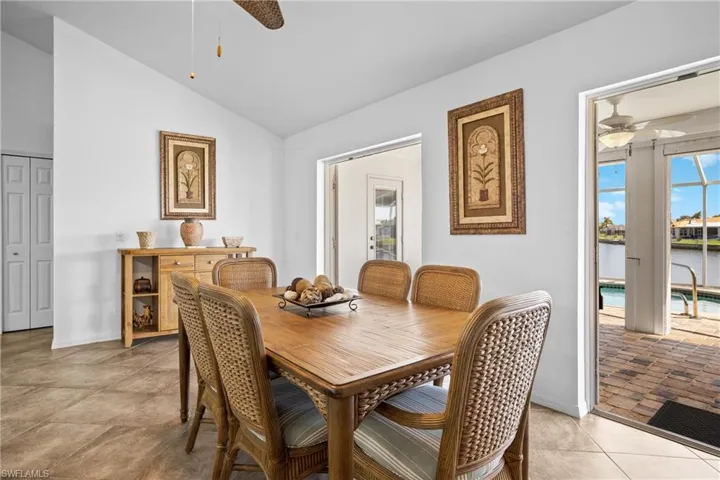 Dining room with light tile patterned floors, vaulted ceiling, and ceiling fan