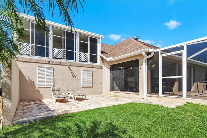 Rear view of property with a lawn, glass enclosure, and a patio area