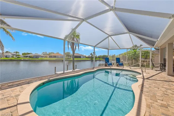 View of swimming pool featuring a lanai, a water view, and a patio