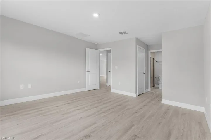 Unfurnished bedroom featuring light wood-style floors, baseboards, connected bathroom, and recessed lighting