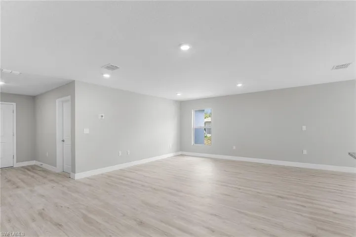 Empty room featuring light wood finished floors, baseboards, and recessed lighting