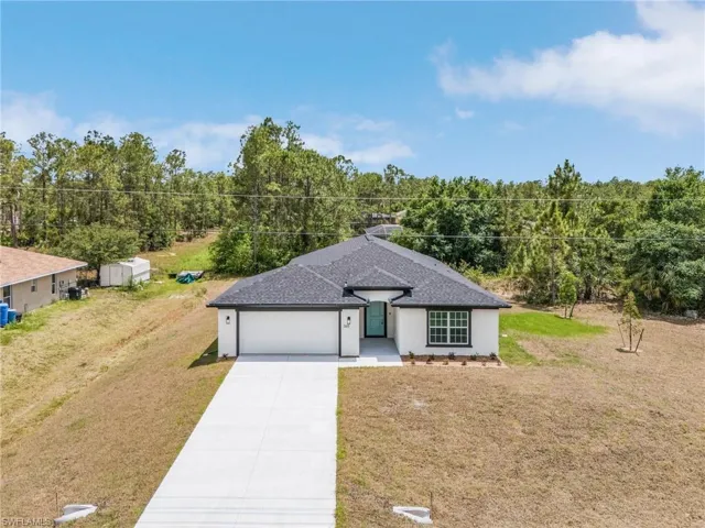 Single story home featuring driveway, a garage, a front yard, and stucco siding