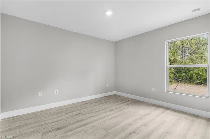 Empty room with light wood-type flooring, baseboards, and a smoke detector