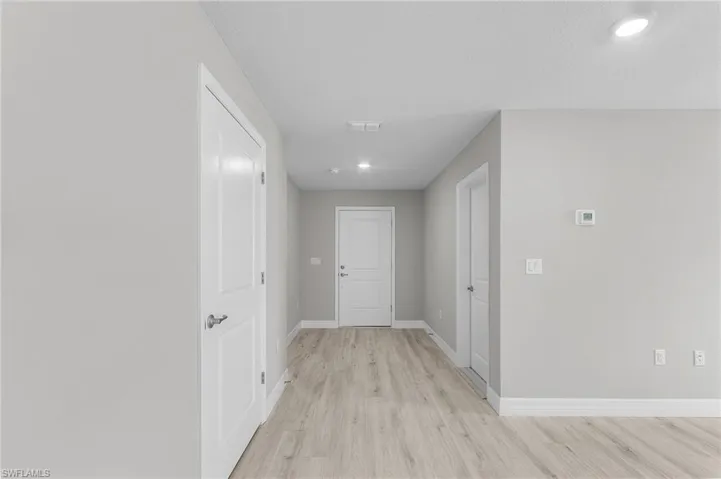 Hallway featuring light wood-type flooring, baseboards, and recessed lighting
