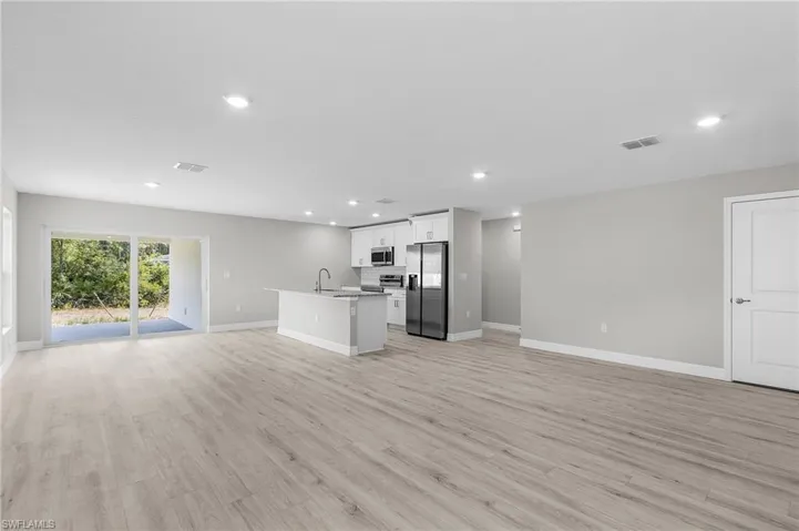 Unfurnished living room with recessed lighting, baseboards, light wood-style floors, and a sink