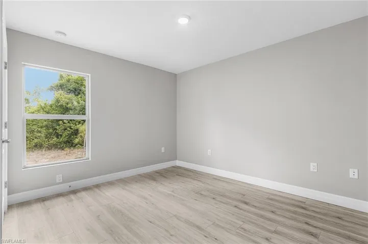 Empty room featuring light wood-style floors, baseboards, and a smoke detector