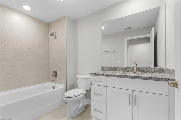 Bathroom featuring toilet, tub / shower combination, vanity, tile patterned flooring, and baseboards