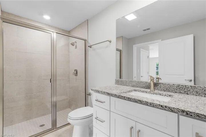 Full bathroom with a stall shower, toilet, vanity, and tile patterned floors