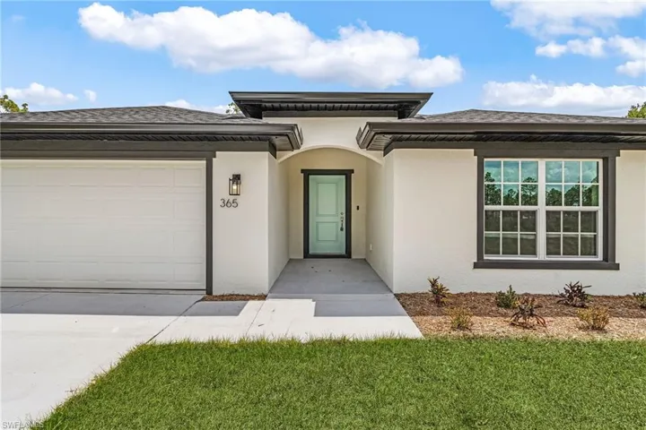 View of front of home with stucco siding, concrete driveway, an attached garage, a shingled roof, and a front yard