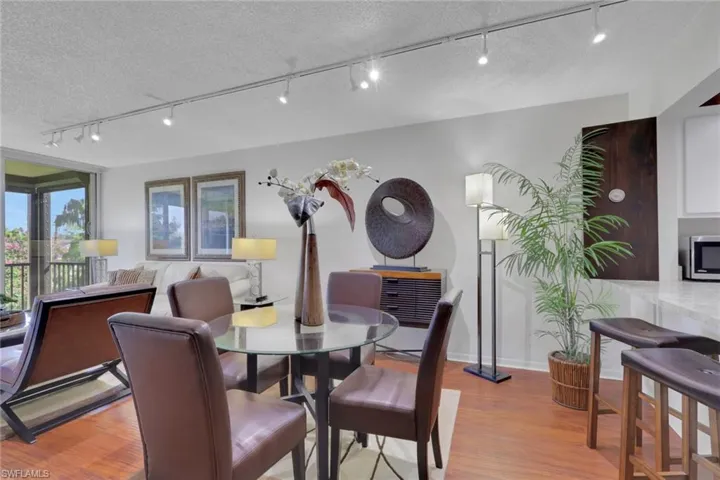 Dining area featuring rail lighting, light wood-style floors, and a textured ceiling