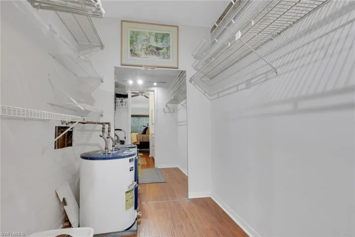 Spacious closet featuring water heater and wood finished floors