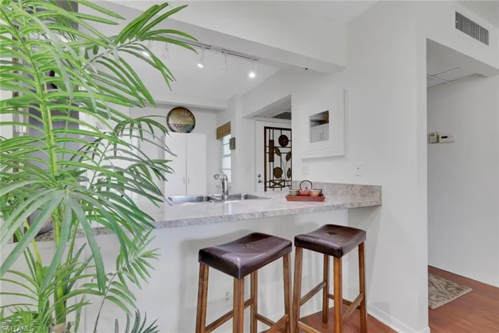 Kitchen featuring a kitchen bar, a peninsula, wood finished floors, and track lighting