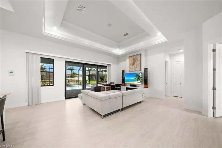 Living area featuring a tray ceiling, ornamental molding, and light wood-style floors