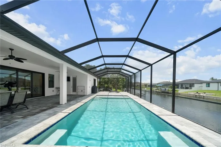 Swimming pool with a water view, ceiling fan, a patio area, and a lanai