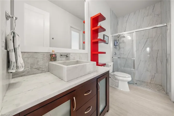 Full bath featuring a marble finish shower, vanity, and wood finished floors