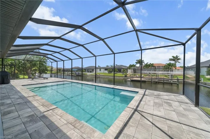 Outdoor pool with a water view, a residential view, a patio area, grilling area, and a lanai