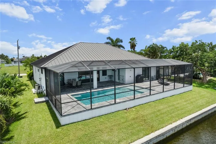 Outdoor pool featuring a patio, a lawn, glass enclosure, and a water view