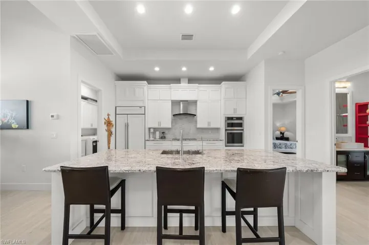 Kitchen featuring backsplash, recessed lighting, light wood-type flooring, white cabinets, and a spacious island