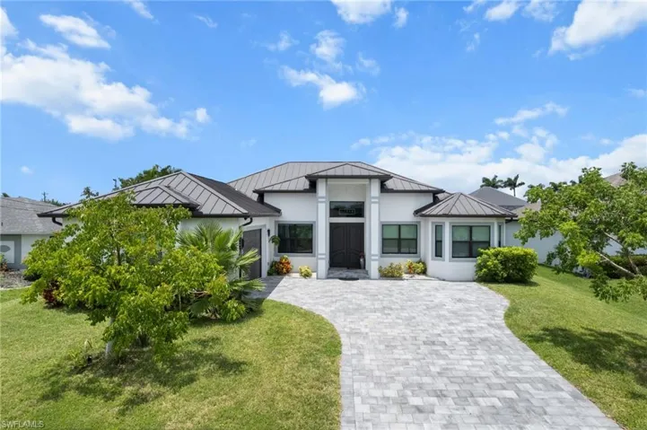 View of front of house featuring a standing seam roof, a metal roof, and decorative driveway