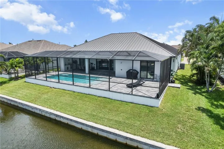 Back of house with a patio area, a water view, a yard, and an outdoor pool
