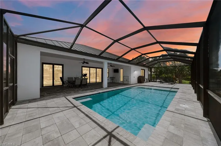 Outdoor pool with a ceiling fan, a patio, glass enclosure, and outdoor dining area