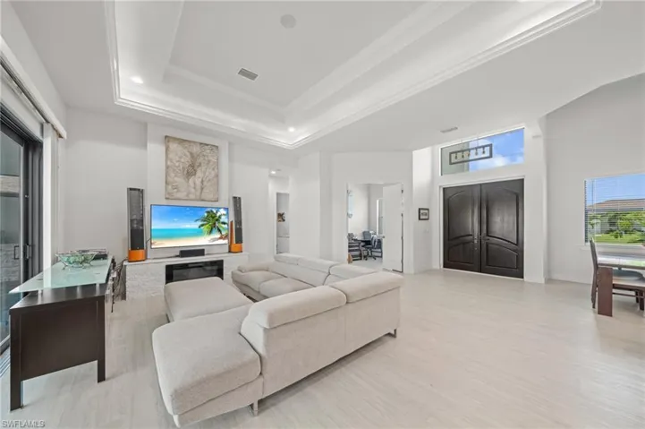 Living area with crown molding, light wood-type flooring, and a raised ceiling