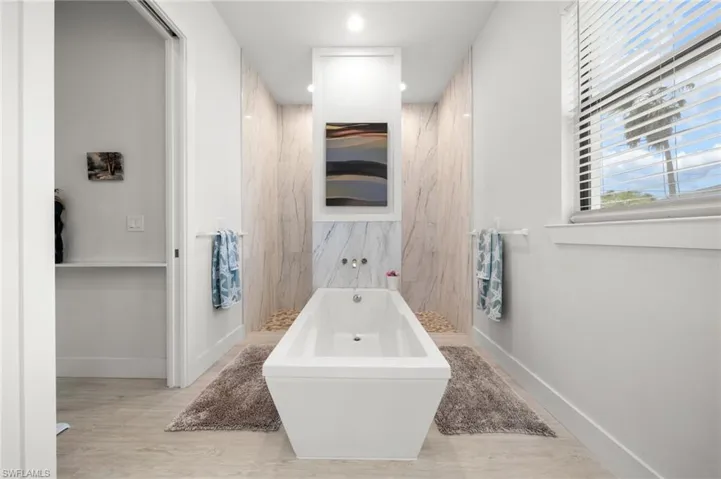 Full bathroom featuring a freestanding tub, recessed lighting, wood finished floors, and a marble finish shower