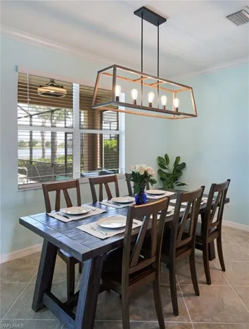 Tiled dining space with crown molding and a chandelier