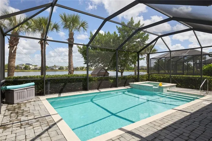 View of pool featuring a water view, a lanai, and an in ground hot tub