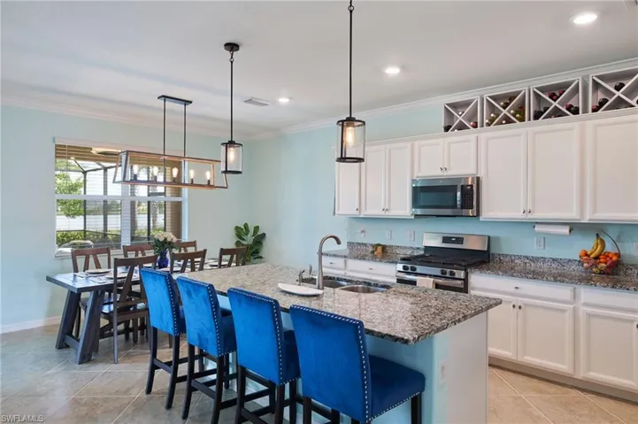 Kitchen featuring pendant lighting, white cabinetry, stainless steel appliances, an island with sink, and sink