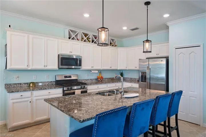 Kitchen featuring light tile patterned floors, stainless steel appliances, an island with sink, and sink
