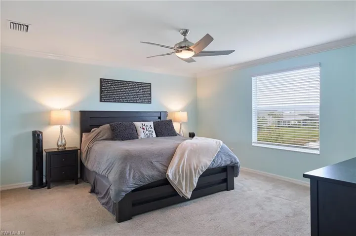 Bedroom with light colored carpet, ceiling fan, and ornamental molding