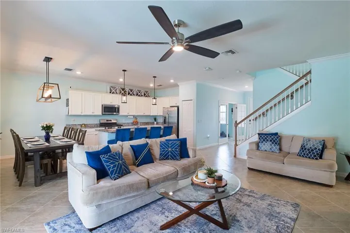 Tiled living room with ornamental molding and ceiling fan