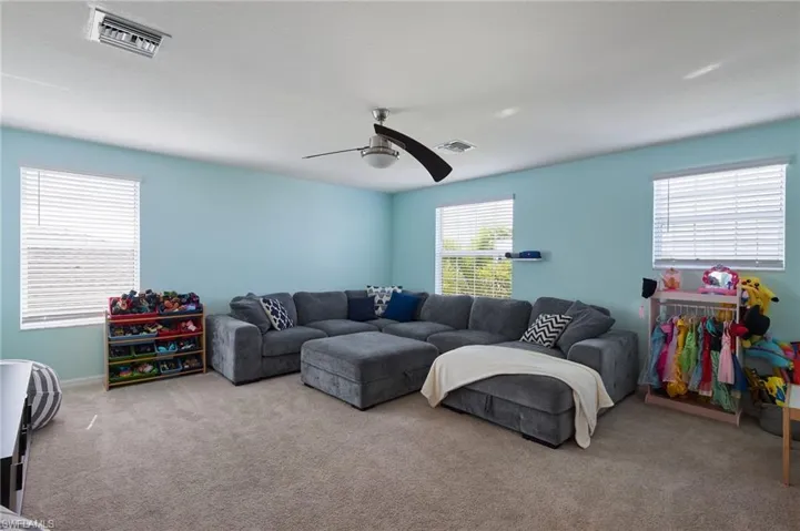 Living room with ceiling fan, a wealth of natural light, and light colored carpet