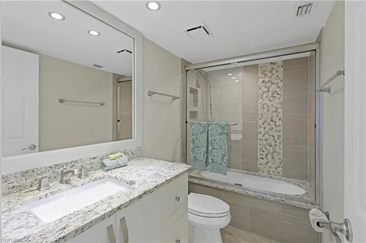 Full bathroom featuring enclosed tub / shower combo, vanity, and toilet