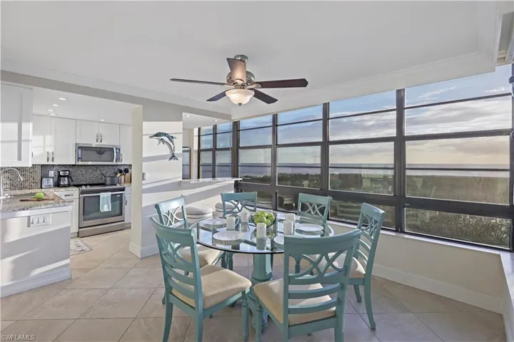 Dining space with light tile patterned floors, ornamental molding, sink, and ceiling fan