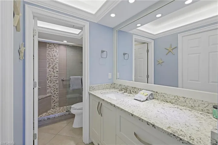 Bathroom featuring tile patterned floors, toilet, crown molding, vanity, and a shower with door