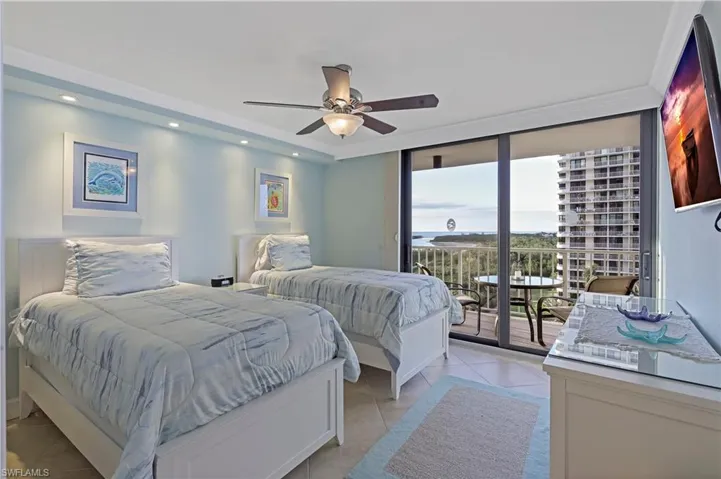 Tiled bedroom featuring ceiling fan, access to exterior, and a wall of windows