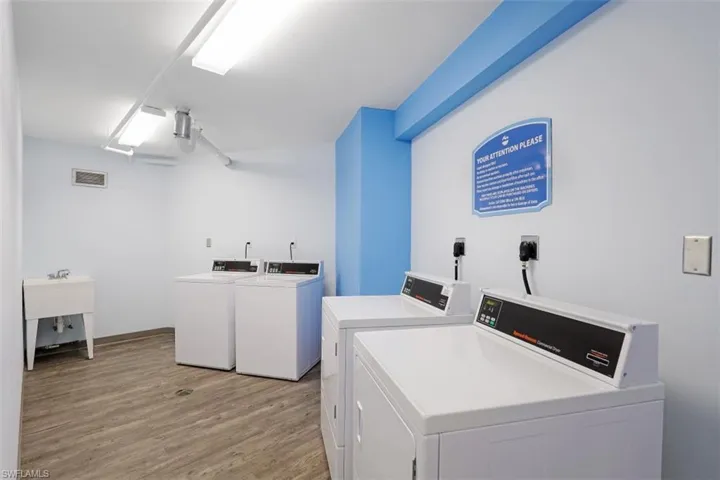 Clothes washing area featuring washing machine and dryer and light wood-type flooring
