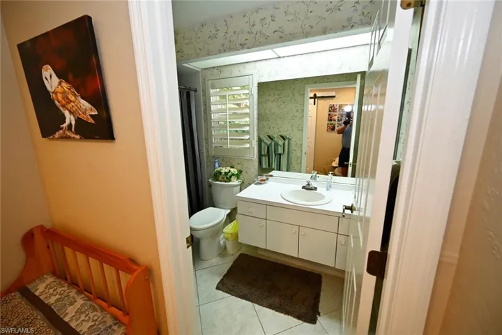 Guest bathroom with walk-in shower, tile floors, and plantation shutter.