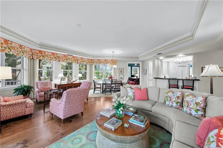 Living room featuring wood-type flooring, a tray ceiling, crown molding, and a chandelier