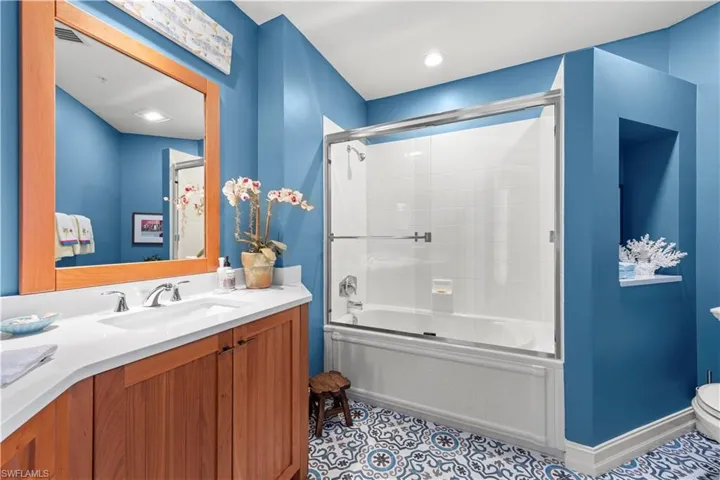 Full bathroom with vanity, toilet, combined bath / shower with glass door, and tile patterned flooring