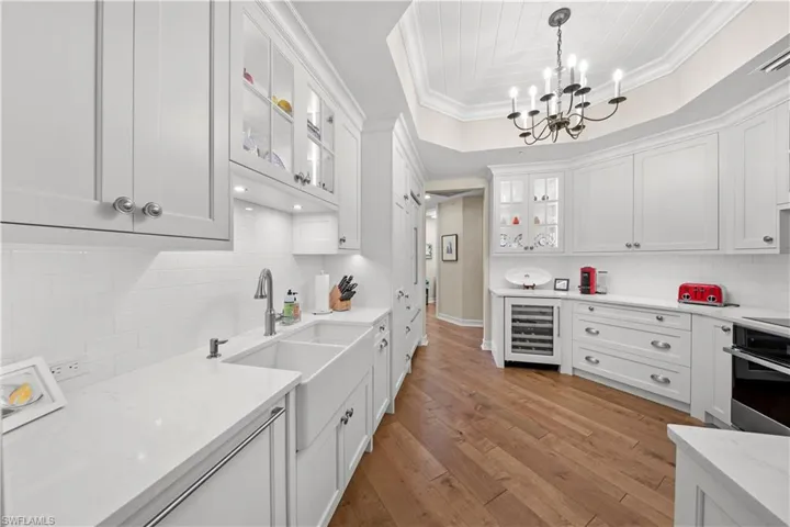 Kitchen featuring light hardwood / wood-style flooring, pendant lighting, wine cooler, white cabinetry, and oven