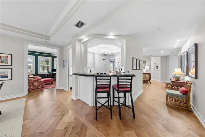 Kitchen with light wood-type flooring, a chandelier, crown molding, and a tray ceiling